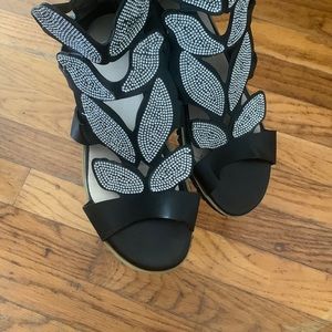 Black flat sandals with a sparkly leaf pattern.